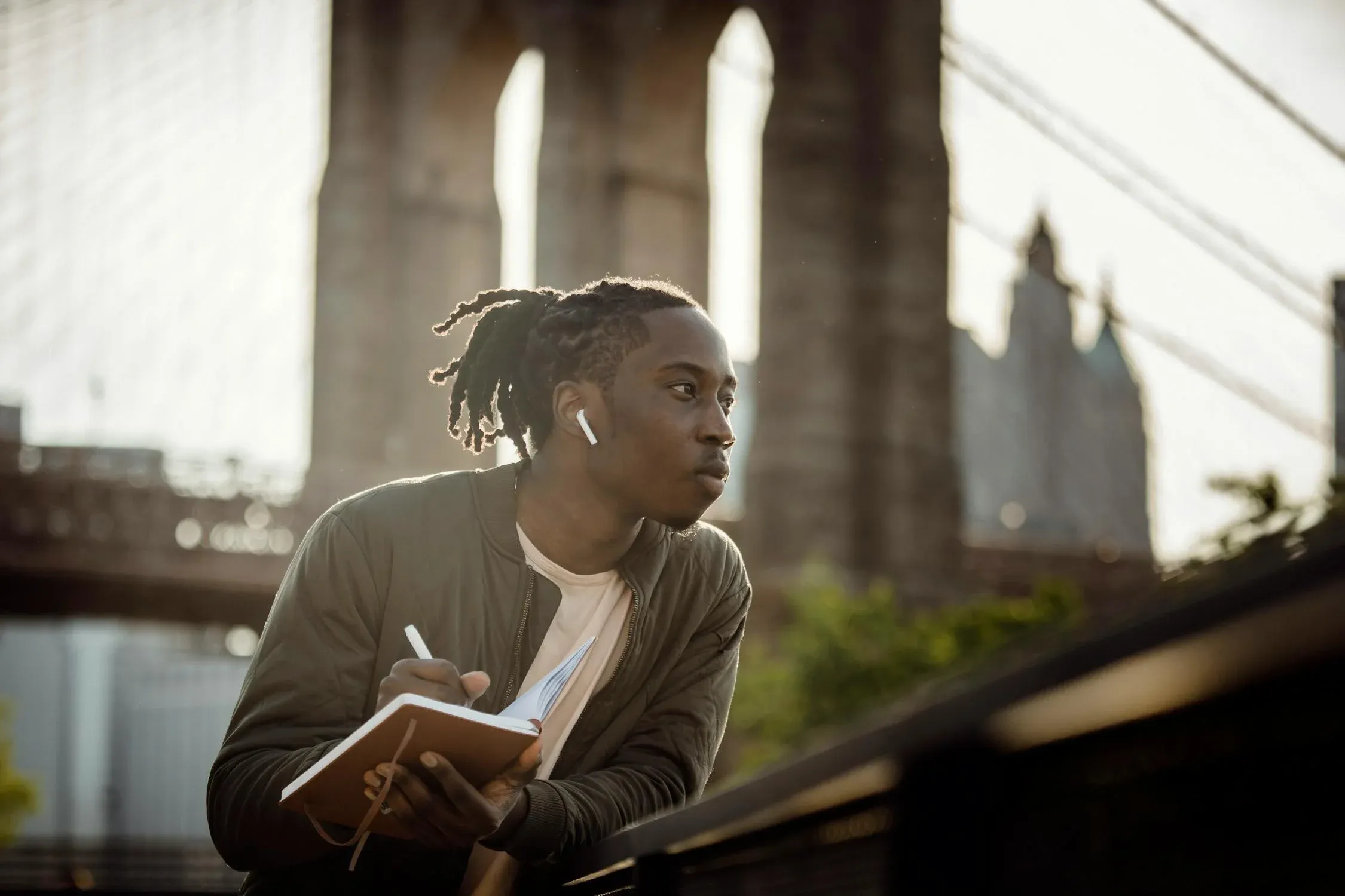 A guy looking to his left writing on a notebook.