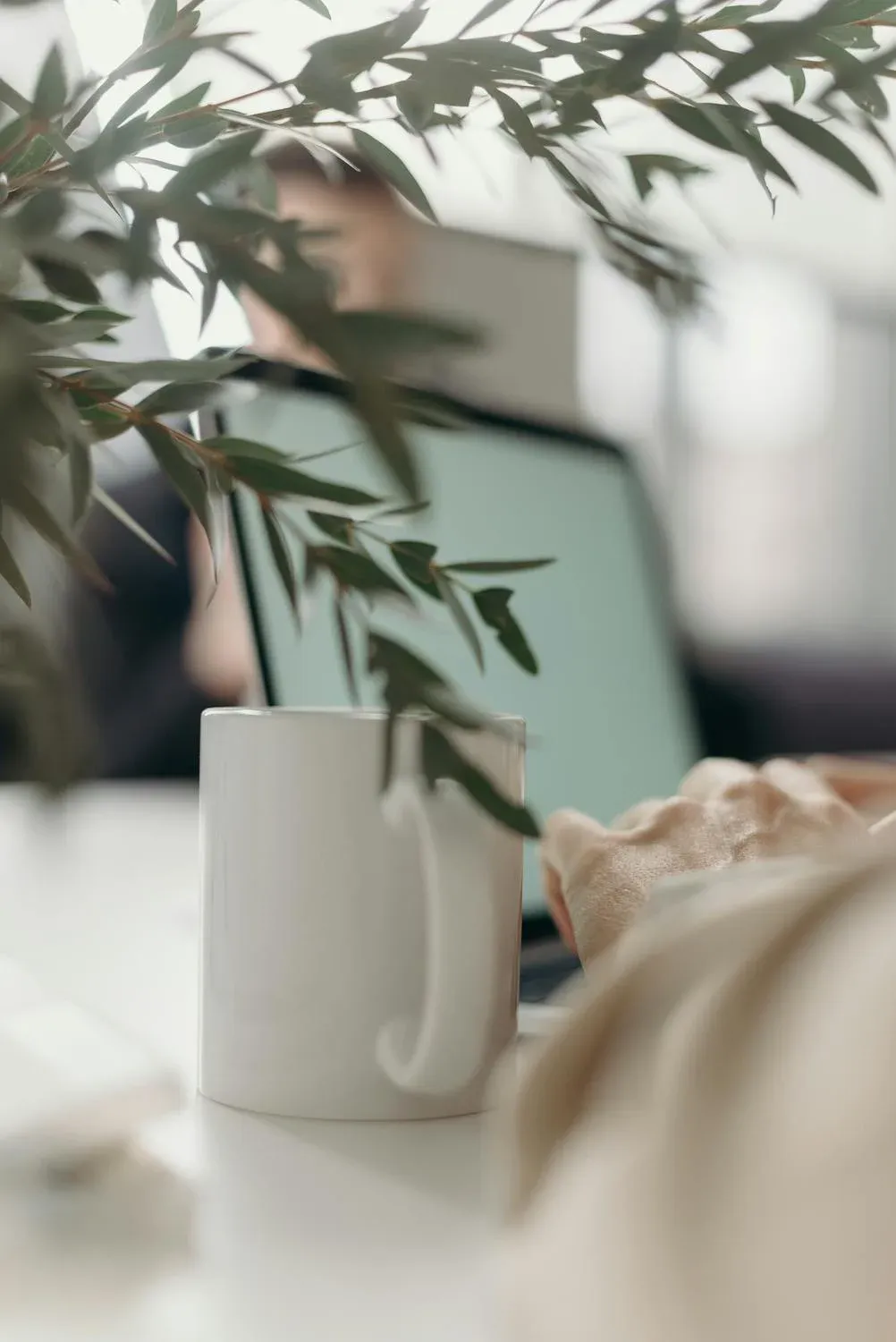 A mug with laptop out of focus in its background.
